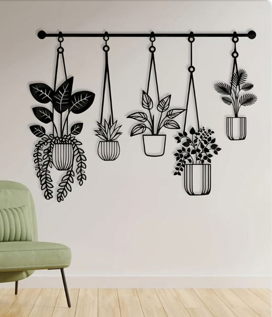 Black metal wall art with five hanging plant pots on a white wall above green chair – minimalist modern home decor