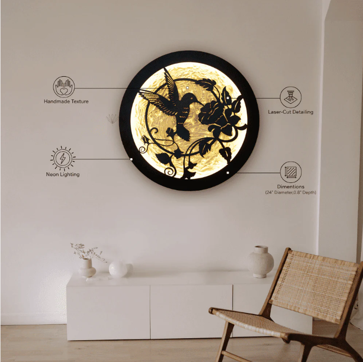 Round LED wall art featuring a laser-cut hummingbird and floral design, backlit with warm neon lighting, mounted on a white wall in a minimalist room.