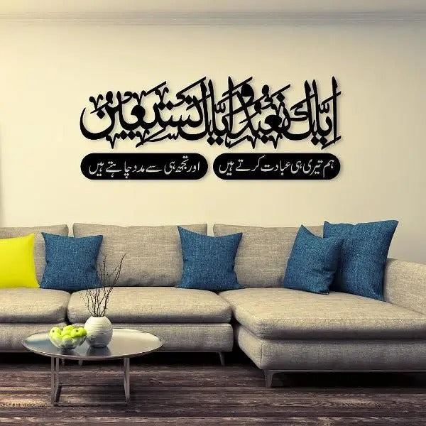 "Islamic wall art above a beige sofa featuring Surah Al-Fatiha in Arabic and Urdu calligraphy."