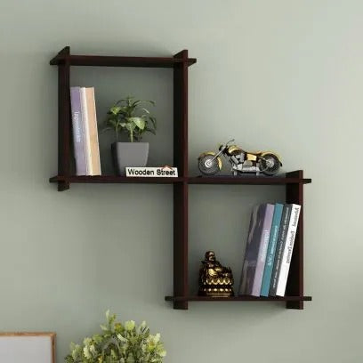 Modern walnut-finish interlocking wall shelf mounted on a light green wall, featuring books, a small potted plant, a miniature motorcycle, and a Buddha figurine for decorative display.