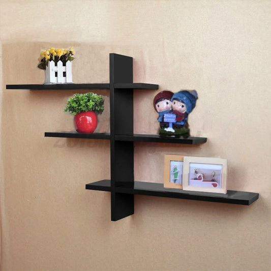 Black wall-mounted decorative shelf with flower pots, figurines, and photo frames on a beige wall