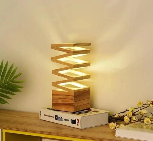 Modern spiral wooden LED table lamp with natural wood finish, placed on a wooden side table beside a flower and decorative bird.