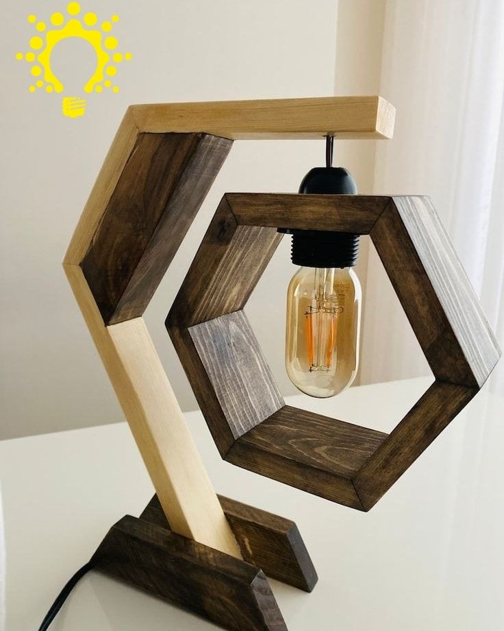 "Geometric hexagon wooden table lamp with Edison bulb, black metal base, and grey socket on a desk"