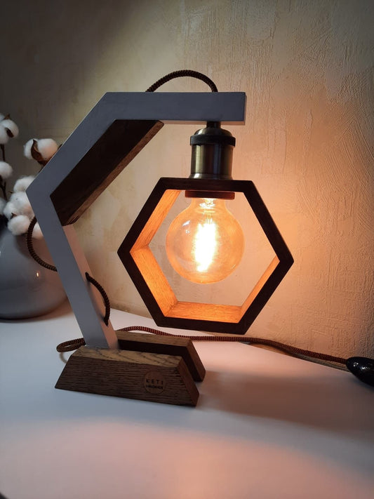 "Geometric hexagon wooden table lamp with Edison bulb, black metal base, and grey socket on a desk"