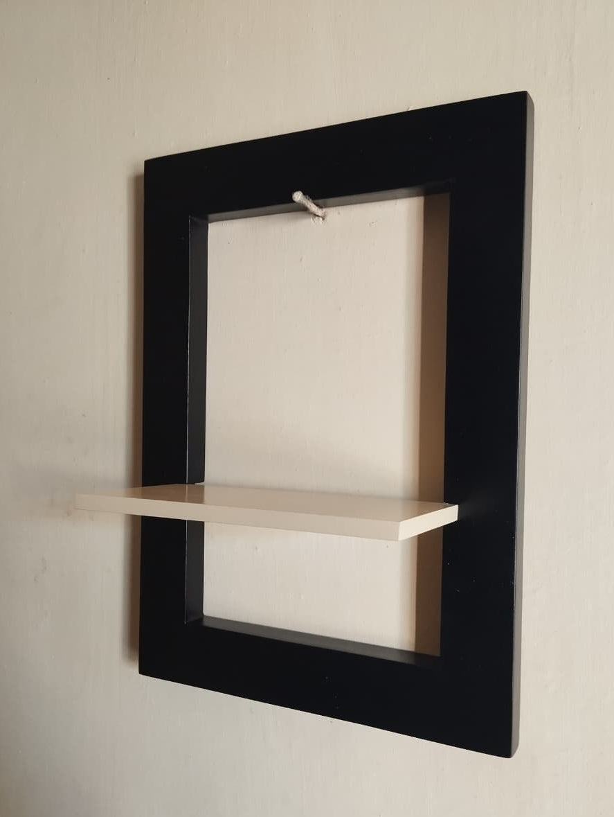 Wall-mounted black frame with a small shelf on a beige wall